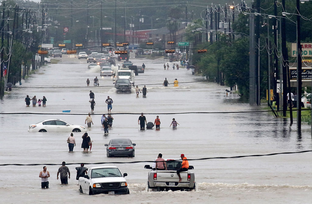 People walk through the flooded waters of Telephone Rd. in Houston on August 27, 2017 as the US fourth city city battles with tropical storm Harvey and resulting floods. Photo by Thomas B. Shea/AFP/Getty Images.