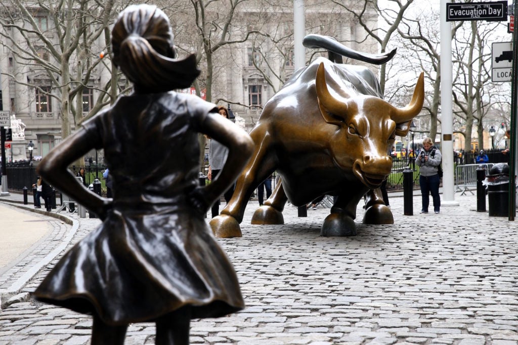 Kristen Visbal's Fearless Girl, a four-foot statue of a young girl, defiantly looks up at Arturo DiModica's iconic Wall Street Charging Bull sculpture in New York City. Fearless Girl was installed for International Women's Day in March to draw attention to the gender pay gap and lack of gender diversity on corporate boards in the financial sector. Courtesy of Volkan Furuncu/Anadolu Agency/Getty Images.