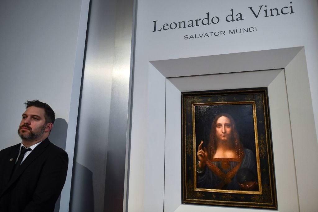 A security personnel stands next to Leonardo da Vinci's 