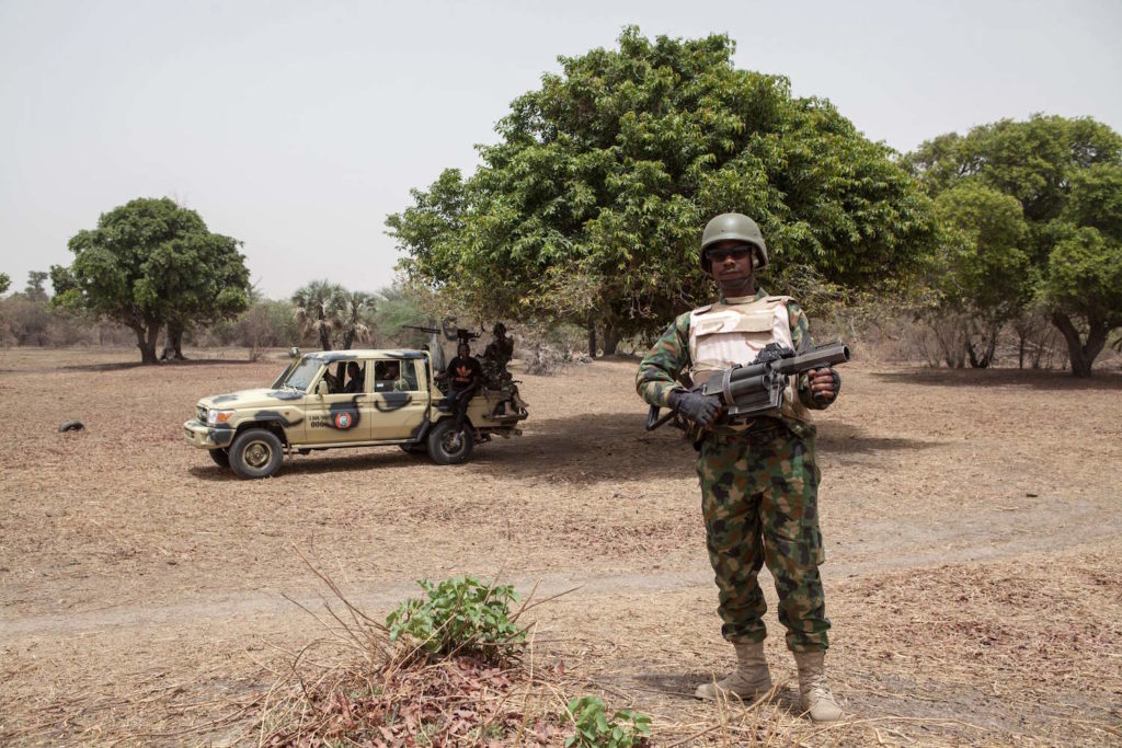 A Nigerian soldier, with a grenade launcher, stands guard near the Yobe river, that separates Nigeria from Niger, on the outskirt of the town of Damasak in North East Nigeria on April, 25 2017 as thousands of Nigerians, who were freed in 2016 by the Nigerian army from Boko Haram insurgents, are returning to their homes in Damasak. Photo courtesy of Florian Plaucheur/AFP/Getty Images.