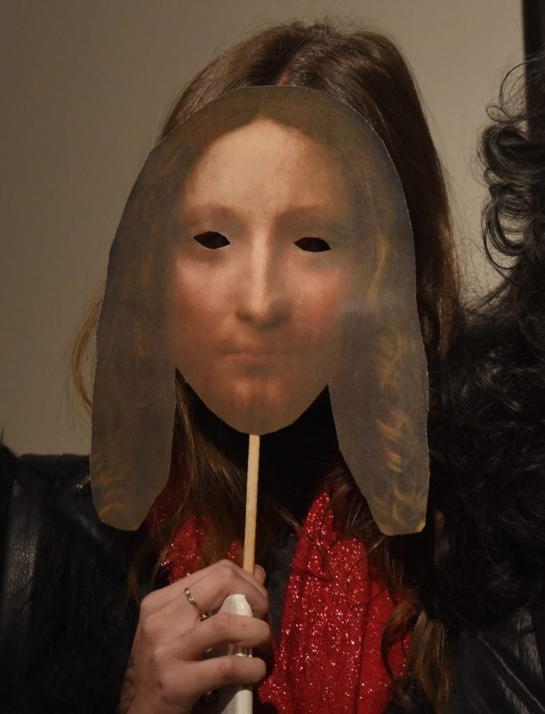 A woman holds up a paddle with the likeness of Leonardo da Vinci's 