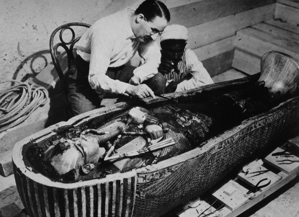 Howard Carter and an Egyptian workman examine the                third coffin of Tutankhamun made of solid gold, inside the                case of the second coffin (October 1925). Photograph by                Harry Burton, courtesy of INTERFOTO/Alamy Stock Photo.