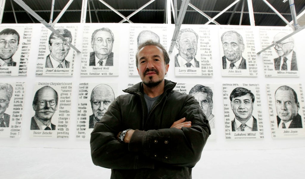 Spanish artist Jose-Maria Cano, poses for photographs in front of some of his portraits at a press view in central London on November 9, 2009 at the Riflemaker Dairy in London. Photo by Shaun Curry/AFP/Getty Images.