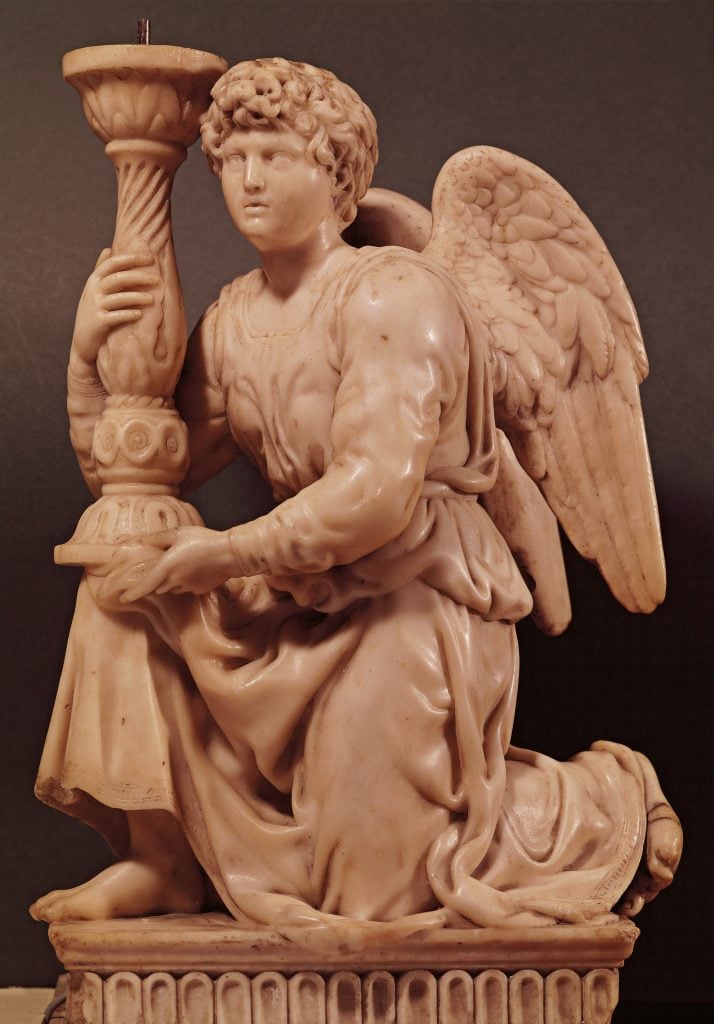 Michelangelo carving of an angel with wings, holding a large candlestick