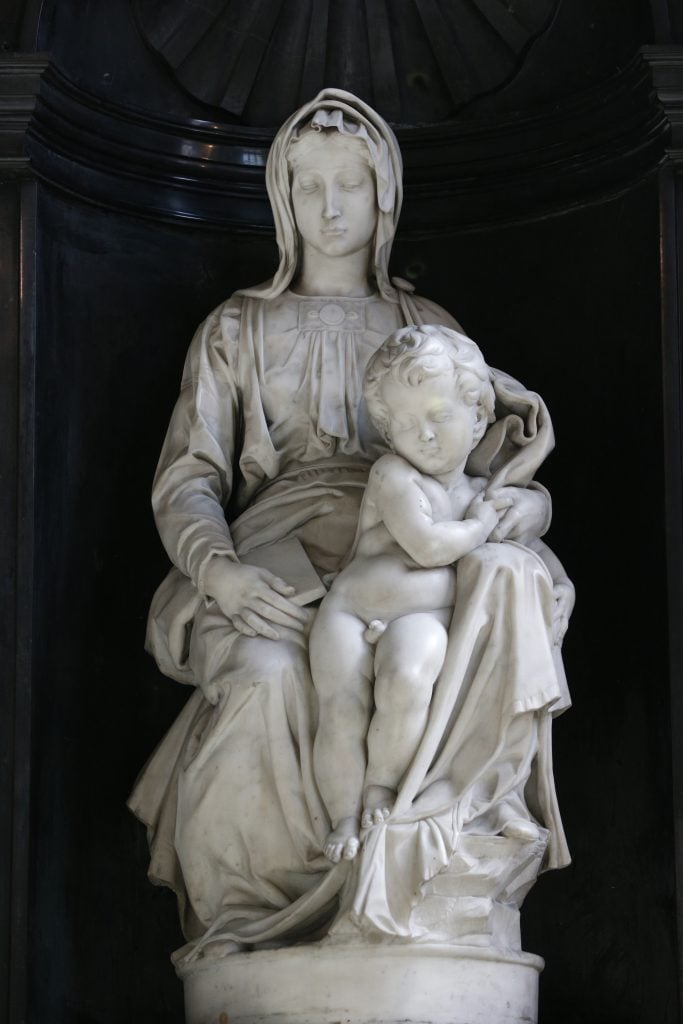 Michelangelo’s Madonna of Bruges: a serene marble sculpture of Mary holding the Christ child with grace.