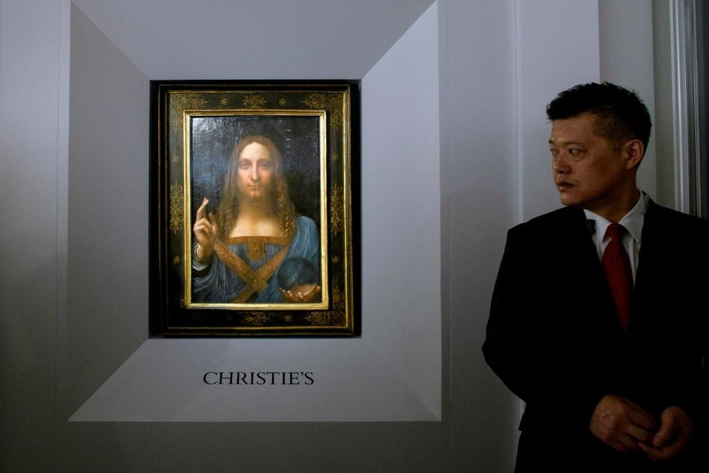 A member of security stands guard next to Leonardo da Vinci's Salvator Mundi painting after it was unveiled in Hong Kong on October 13, 2017. Photo by Anthony Wallace /AFP/Getty Images.