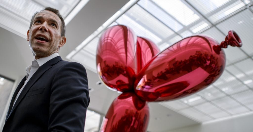 US artist Jeff Koons' poses next to Balloon Dog (Red) in 2012. Photo by Fabrice Coffrini/AFP/Getty Images.