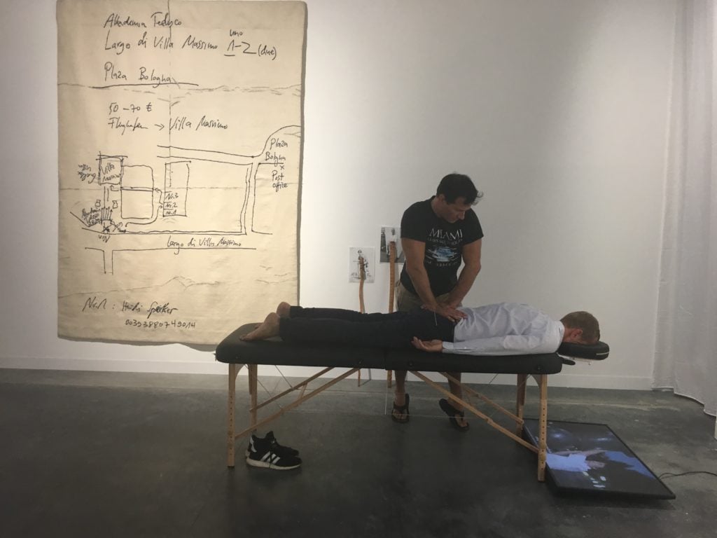 Christian Jankowski receiving a massage as part of his installation at joségarcía's booth at Art Basel Miami Beach.