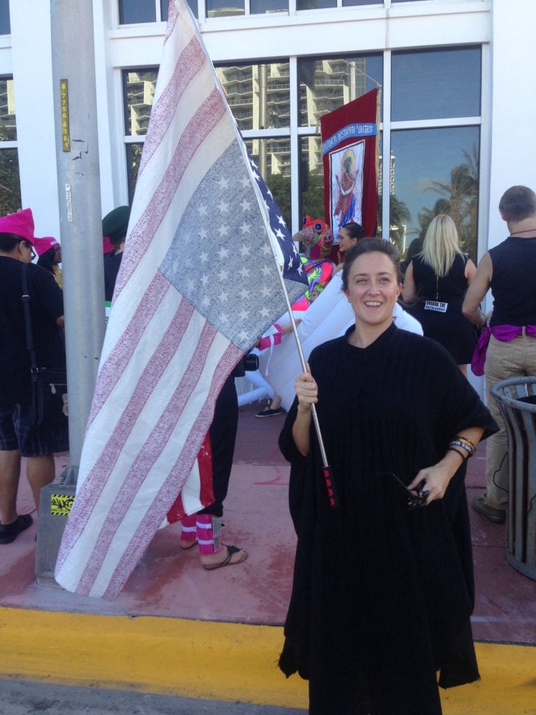 Ann Lewis with her flag inscribed with Donald Trump's false statements, marching in Michele Pred's <em>Parade Against Patriarchy</em>. Photo courtesy of Sarah Cascone.