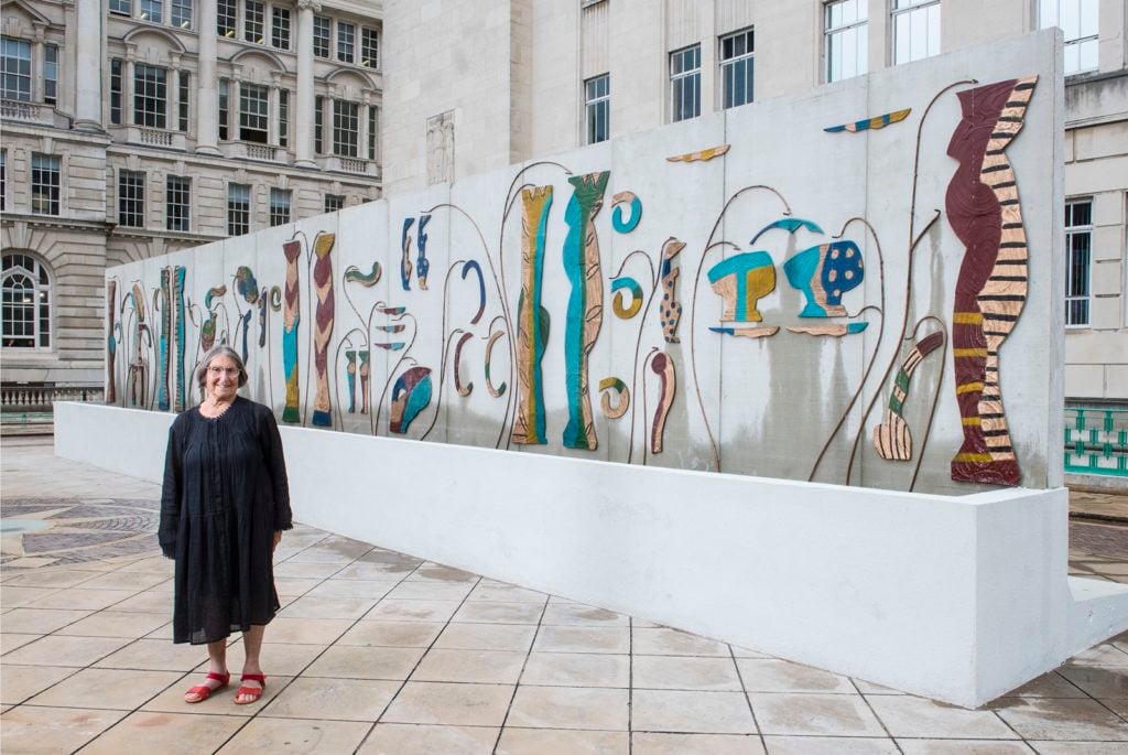 Betty Woodman with her work <i>Liverpool Fountain</i> (2016), at George's Dock, Liverpool, England. Photo Joel Chester Fildes, Liverpool Biennial, 2016.