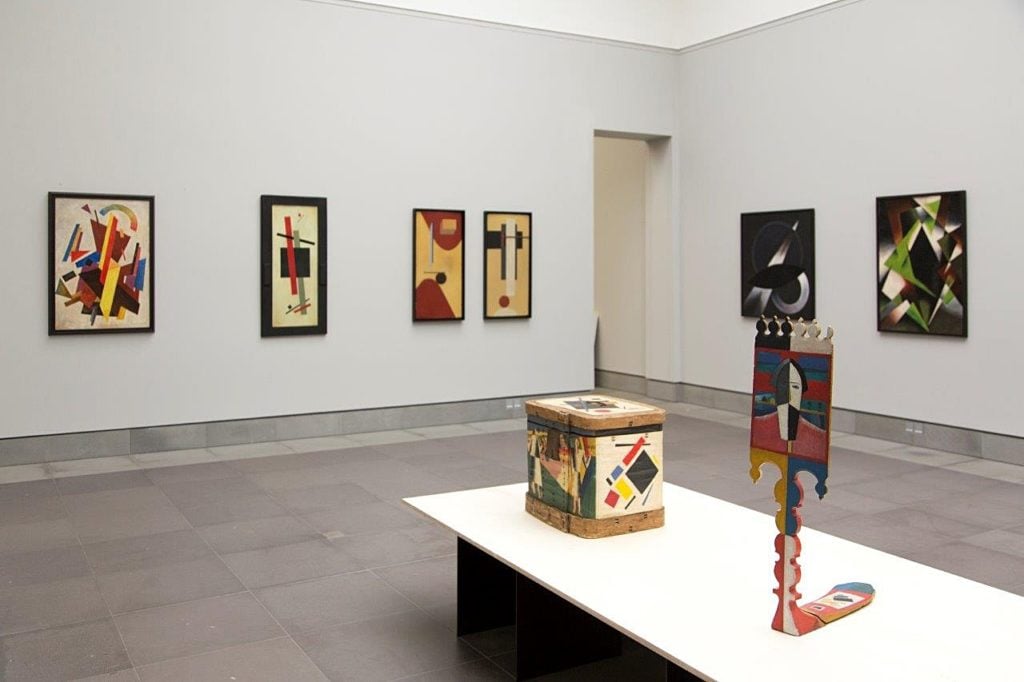 In background, paintings on the walls purportedly by Olga Rozanova, Kazimir Malevich, El Lissitzky; works by Alexander Rodchenko and Lyubov Popova (far right). Image courtesy of the Museum of Fine Art in Ghent.