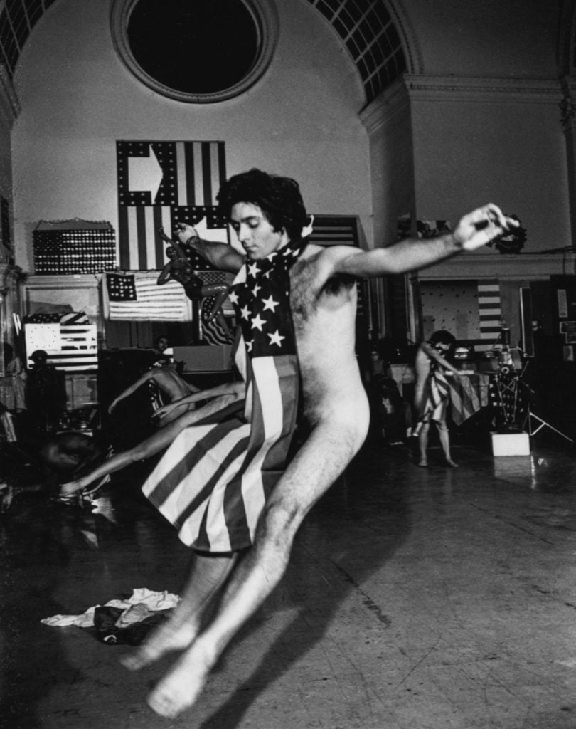 David Gordon in a performance of <em>Trio A With Flags</eM> at Judson Memorial Church in 1970. Photograph by Peter Moore/©Barbara Moore/VAGA, NY.