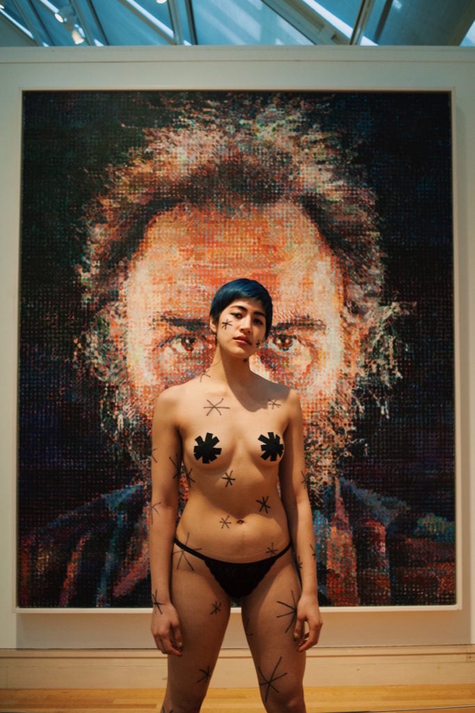 Emma Sulkowicz's protest performance, with a Chuck Close painting at the Metropolitan Museum of Art. Photo courtesy of Sangsuk Sylvia Kang.