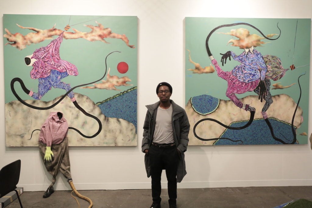 Artist Simphiwe Ndzube with his paintings at Nicodim Gallery. Photo: Henri Neuendorf.