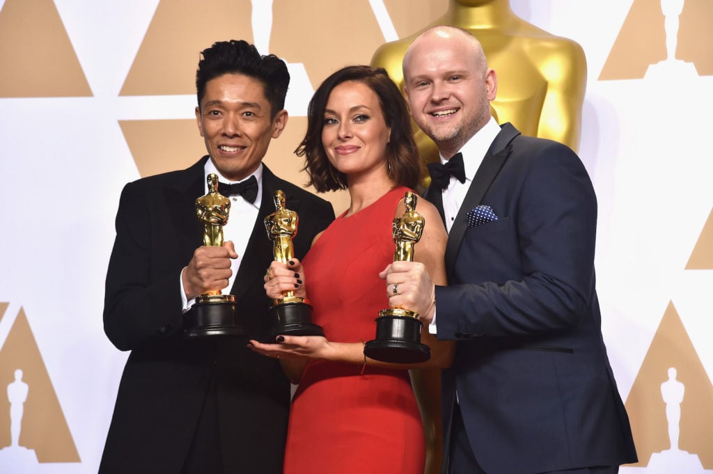 Kazuhiro Tsuji, Lucy Sibbick, and David Malinowski, winners of the Best Makeup for <em>The Darkest Hour</em>, pose in the press room during the 90th Annual Academy Awards. Photo courtesy of Alberto E. Rodriguez/Getty Images.