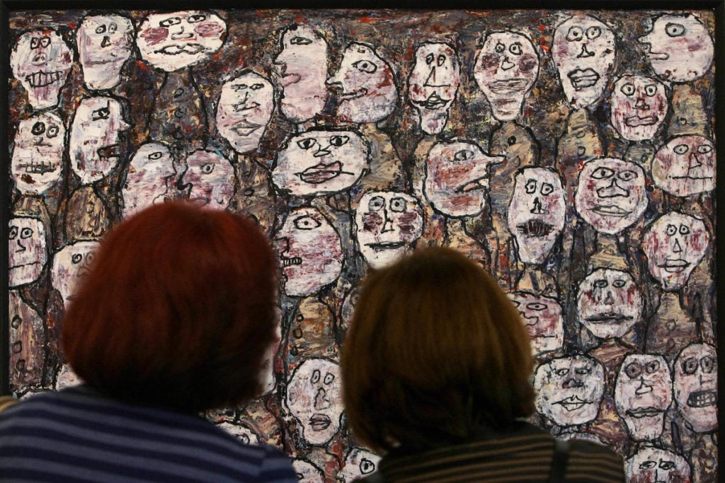 Visitors look at thr painting <em>Affluence-1961</em> during the retrospective of Jean Dubuffet (1901-1985) in Sao Paulo, Brazil, on July 16, 2009. Image courtesy Mauricio Lima/AFP/Getty Images.
