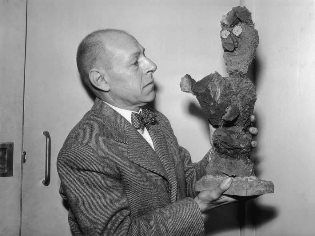 Jean Dubuffet with one of his volcanic lava sculptures entitled <em>Madame j'ordonne</em> (1954), March 29 1955. Photo by Harry Todd/Fox Photos/Hulton Archive/Getty Images.