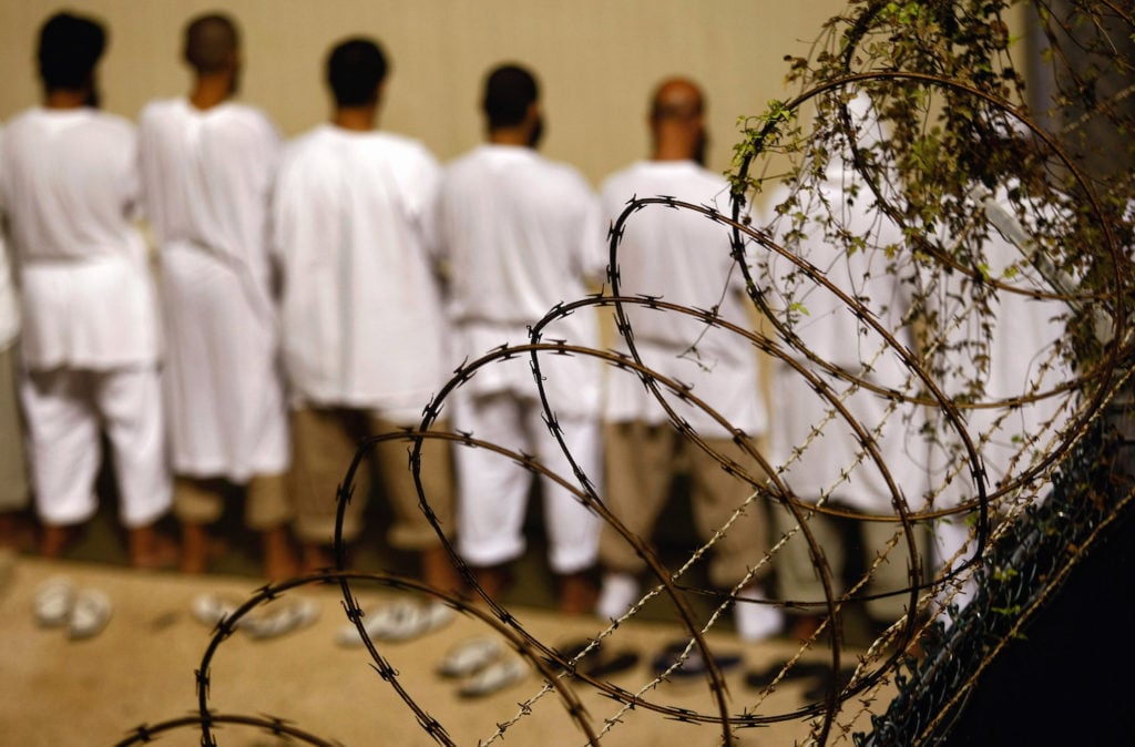 Detainees stand during an early morning Islamic prayer at the Guantánamo Bay US military prison. Photo by John Moore/Getty Images.