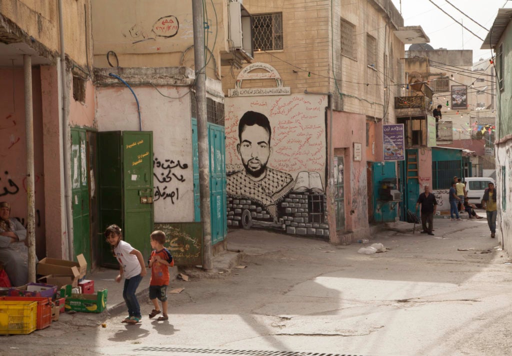 A photo from Margaret Olin's "Marking Time" series, documenting the tribute murals to Palestinians on street walls and buildings in the Dheisheh Refugee Camp just south of Bethlehem on the West Bank. Photo courtesy of the Palestine Museum US.