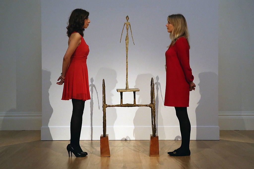 Employees pose next to a sculpture by Italian artist Alberto Giacometti entitled <em>Chariot</em> during a press preview at Sotheby's on October 10, 2014 in London, England. Photo by Carl Court/Getty Images.