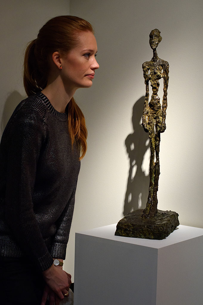 A guest views <em>Femme Debout</em> by artist Alberto Giacometti during the preview ahead of the artist's muse: a curated evening sale in Christie's New York on October 9, 2015 in London, England. Photo by Ben Pruchnie/Getty Images.