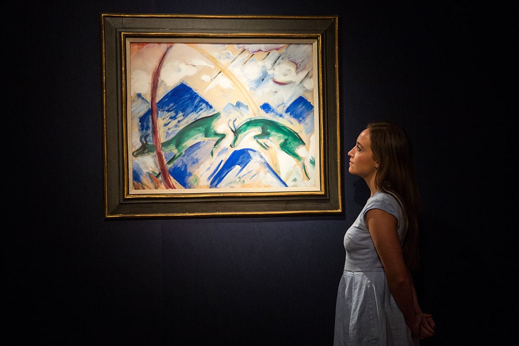 A member of staff poses beside Franz Marc's 1991 piece <em>Gemsen</em>, estimated at between £1.8-2.5 million, at Christie's King Street auction house on June 19, 2015 in London, England. Photo by Rob Stothard/Getty Images.