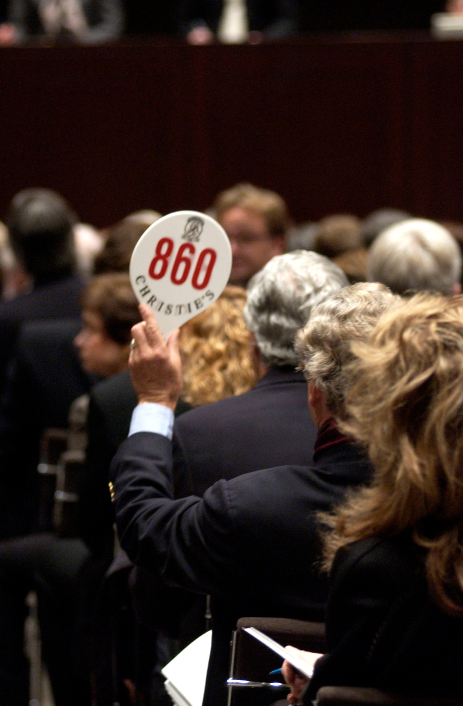 A bidder raises his paddle at Christie's in Rockefeller Center in New York City. Photo by Fernando Leon/Getty Images.