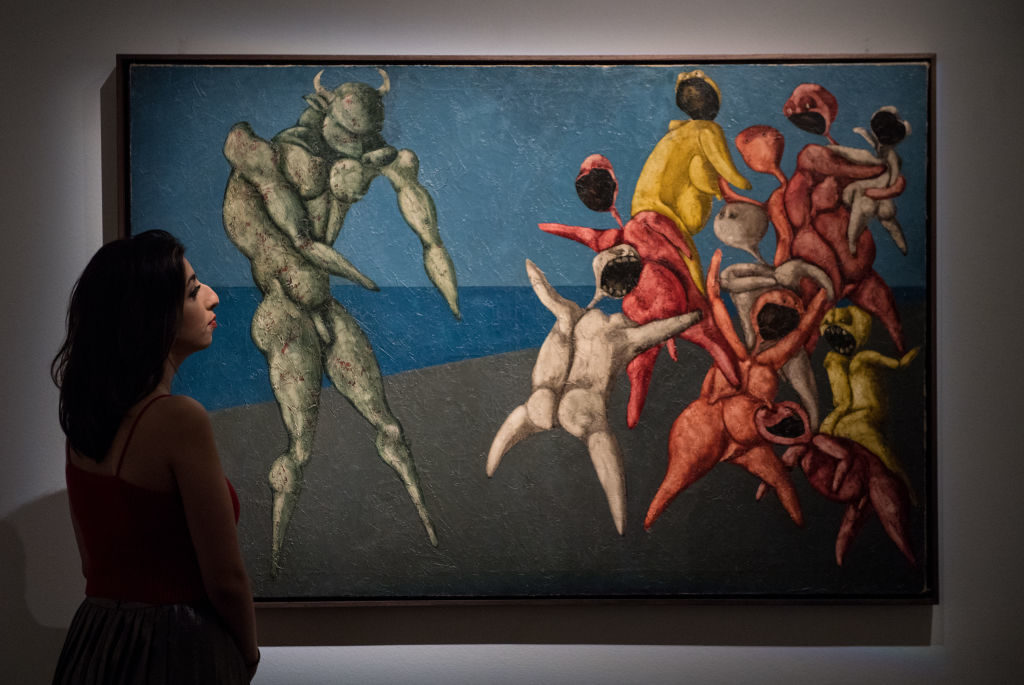 A Sotheby's employee poses next to <em>Il Minotauro fa Paura alla Gente per Bene</em> by Bahman Mohasses during a press preview of Orientalist and Middle Eastern Art Week at Sotheby's on April 20, 2018 in London, England. Photo by Chris J Ratcliffe/Getty Images for Sotheby's.