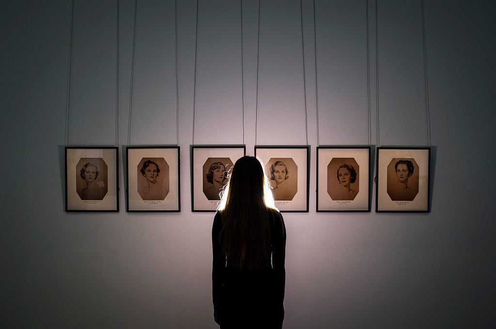 A Sotheby's employee stands in front of a series of portraits of the Mitford Sisters during the pre-auction preview of the personal collection of Deborah Cavendish, Duchess of Devonshire at Sotheby's on February 26, 2016 in London, England. Photo by Justin Setterfield/Getty Images.