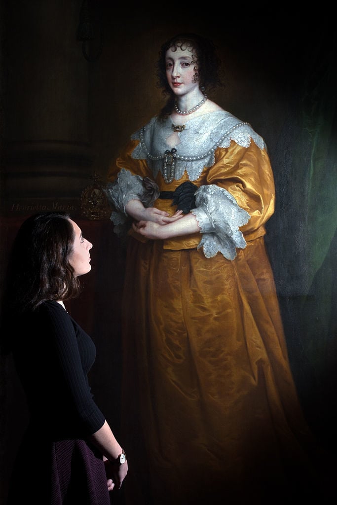 A member of staff poses next to a painting by Sir Anthony Van Dyck entitled <em>Portrait of Queen Henrietta Maria,/em> during a press preview at Sotheby's on December 4, 2015 in London, England. Photo by Carl Court/Getty Images.