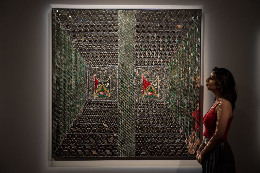 A Sotheby's employee poses next to <em>Recollections I</em> by Monir Farmanfarmaian during a press preview of Orientalist and Middle Eastern Art Week at Sotheby's on April 20, 2018 in London, England. Photo by Chris J Ratcliffe/Getty Images for Sotheby's.