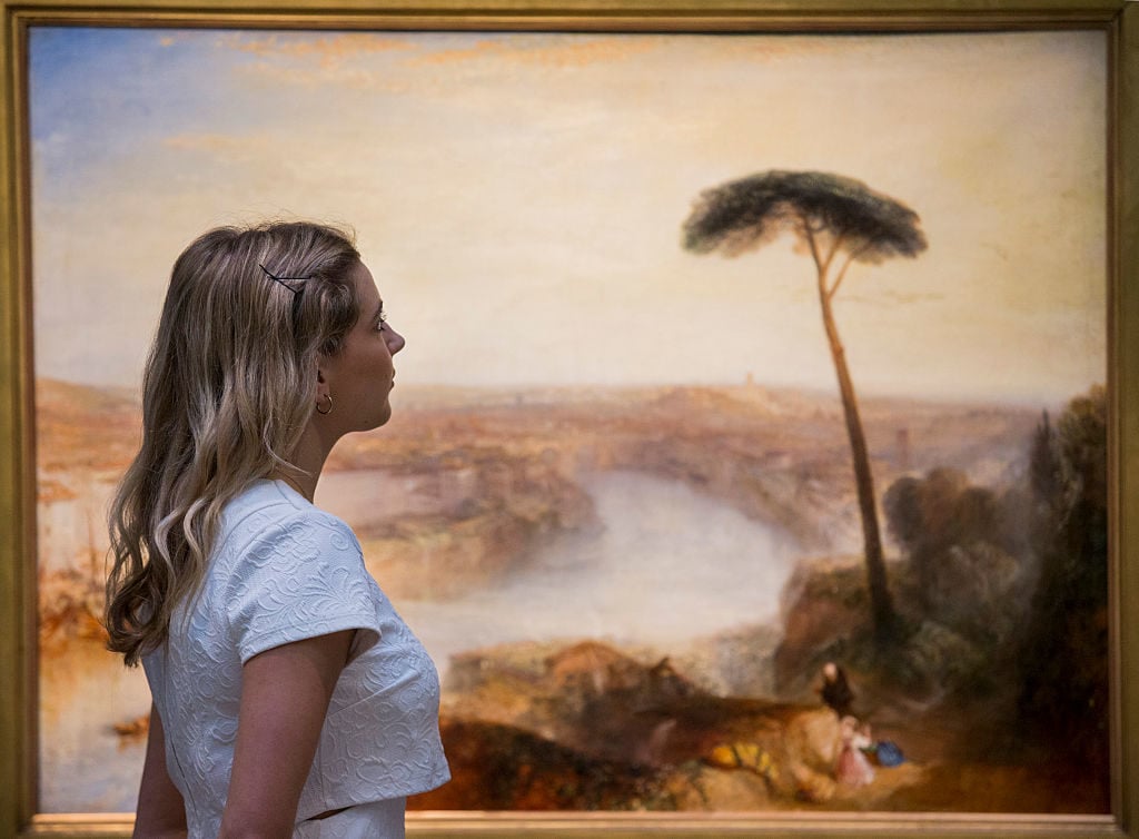 A Sotheby's auction house employee views <em>Rome, from Mount Aventine</em> by J.M.W. Turner on November 28, 2014 in London, England. Photo by Rob Stothard/Getty Images.