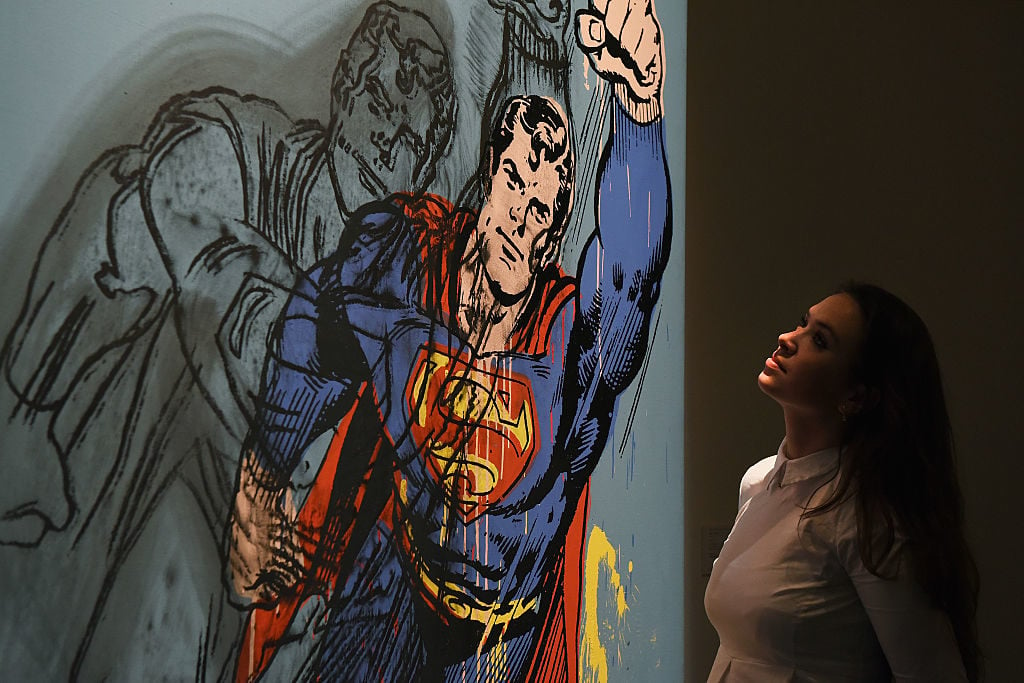 A gallery assistant looks up at Andy Warhol's <em>Superman</em> (1981) (estimated in the region of $6/8m), which has gone on show at Sotheby's on April 10, 2015 in London, England. Photo by Mary Turner/Getty Images for Sotheby's.