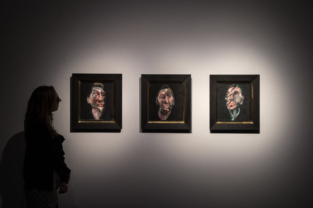Christies employees pose for photos with <em>Three studies for a portraits of George Dyer</em> by Francis Bacon, estimated at $50-$70 million, at Christies on February 24, 2017 in London, England. Photo by Chris J Ratcliffe/Getty Images.