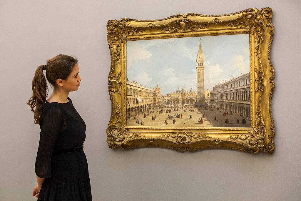A Sotheby's auction house employee views <em>Venice, a view of Piazza San Marco looking east towards the Basilica</em> by Canaletto on November 28, 2014 in London, England. Photo by Rob Stothard/Getty Images.