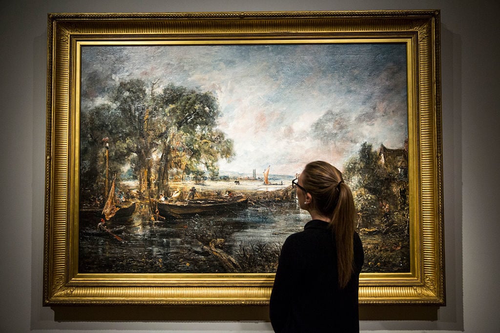 A Christie's employee poses with <em>View on the River Stour near Dedham</em> circa 1821-1822 by English painter John Constable at the auction house on May 26, 2016 in London, England. Photo by Jack Taylor/Getty Images.