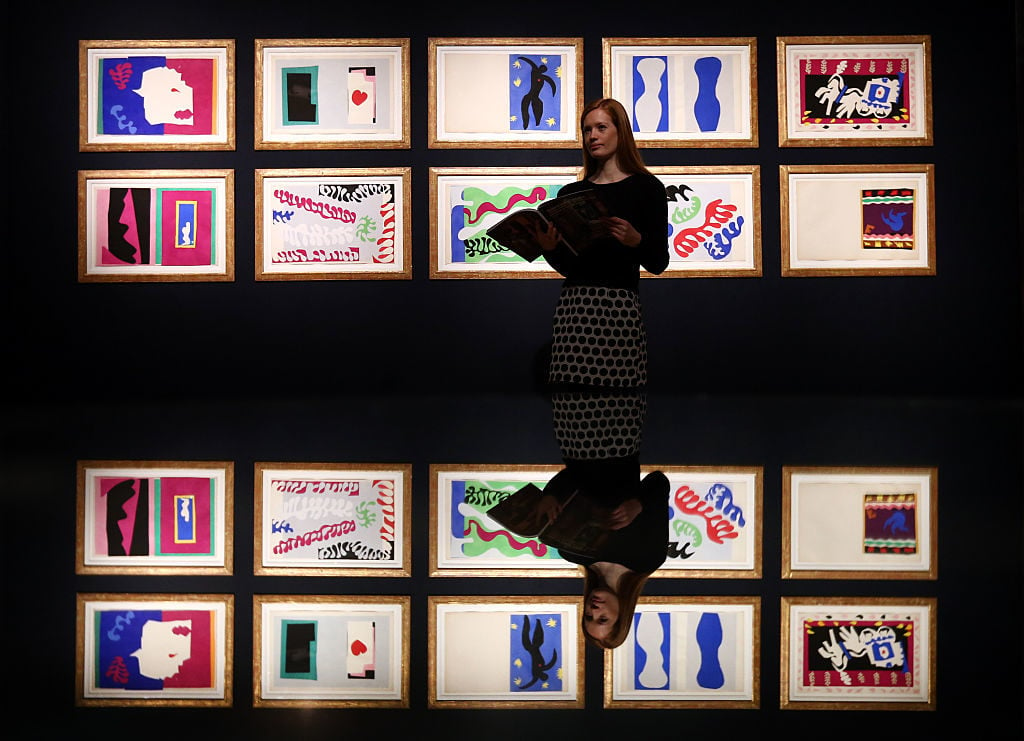 A member of staff is reflected as she poses next to a collection of Henri Matisse original prints from his jazz portfolio at Christie's auction house on February 17, 2016 in London, England. Photo by Carl Court/Getty Images.