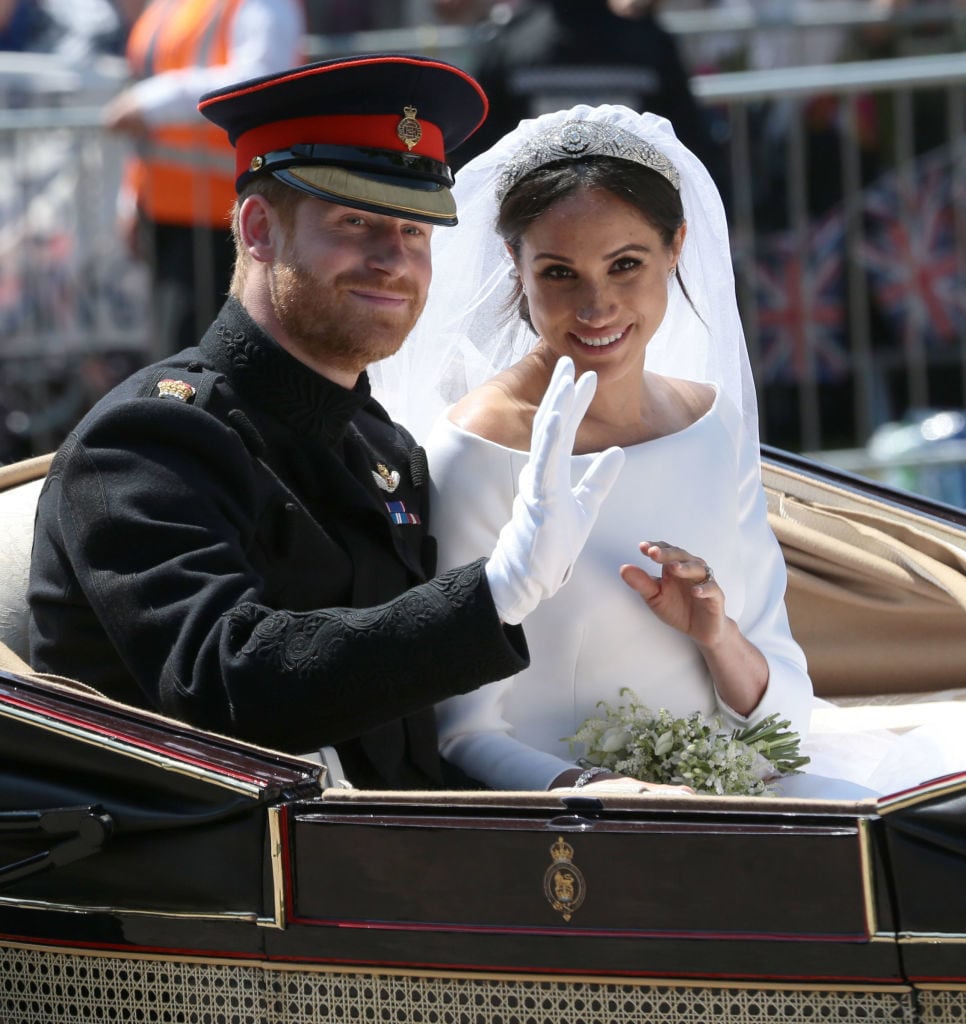Prince Harry, Duke of Sussex and Meghan, Duchess of Sussex wave from the Ascot Landau Carriage during their carriage procession on Castle Hill outside Windsor Castle in Windsor, on May 19, 2018 after their wedding ceremony. Photo by Aaron Chown/WPA Pool/Getty Images.