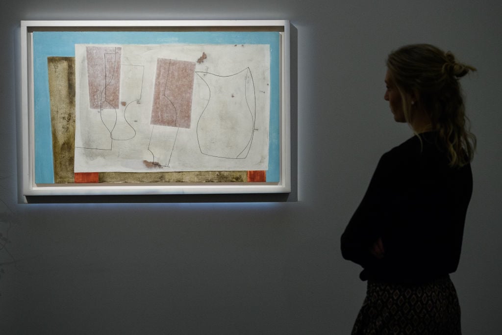 A gallery assistant poses with <em>Sept 58 (Iseo)</em> (est £400,000-600,000) by Ben Nicholson, at Sotheby's auction house on November 17, 2017 in London, England. Photo by Leon Neal/Getty Images