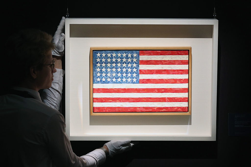 A Sotheby's employee poses with Jasper Johns's <i>Flag</i>. Photo by Carl Court/Getty Images.
