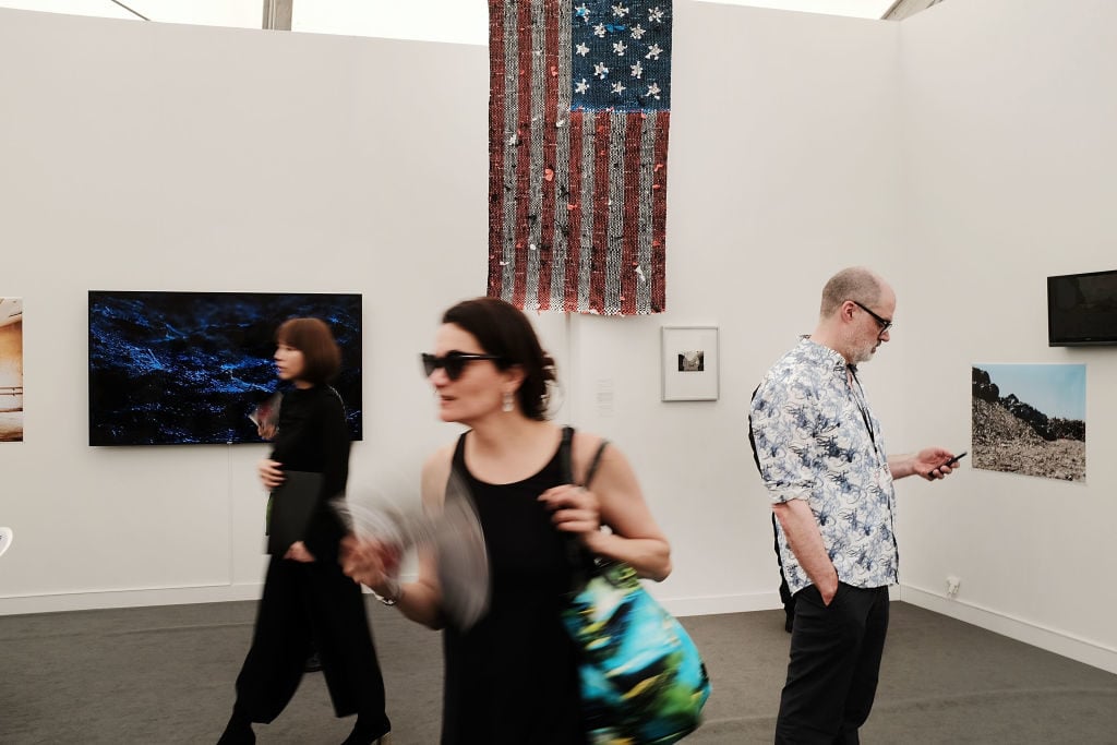 A woman fans herself walking through exhibits at the New York Frieze Art Fair on on May 3, 2018 in New York City. Photo by Spencer Platt/Getty Images.