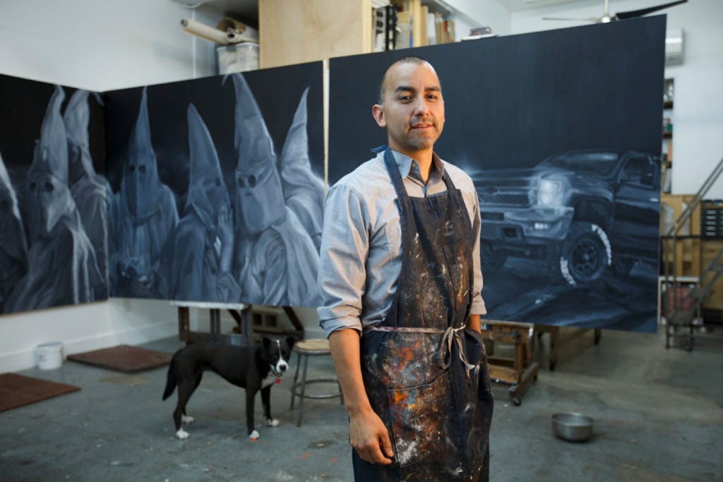 Mexican American artist, Vincent Valdez working on The City I, a painting of modern day klansmen, in his studio in San Antonio. Photo by Michael Stravato, courtesy of the Blanton Museum of Art at the University of Texas at Austin.