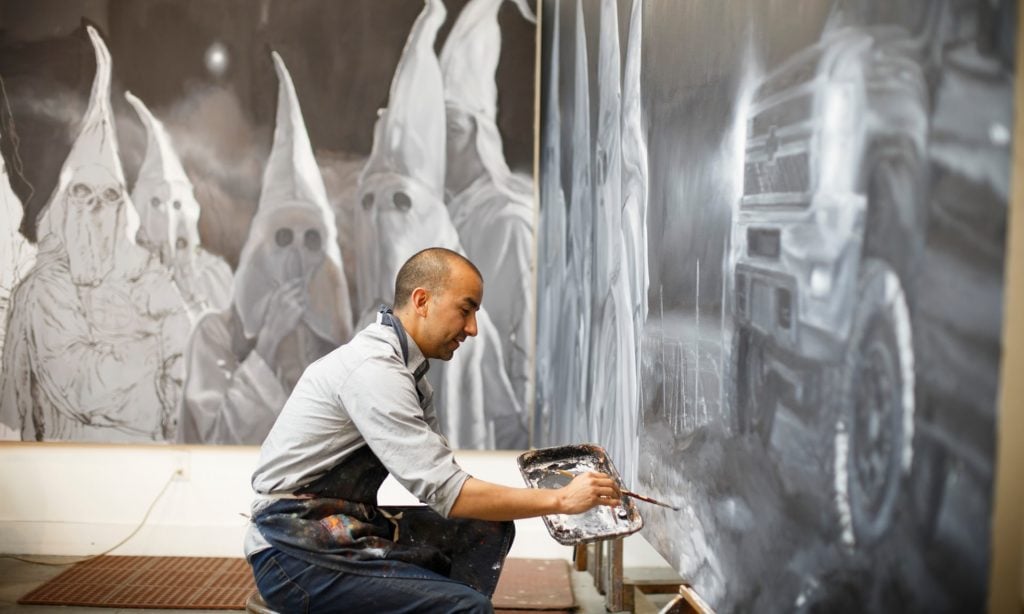 Vincent Valdez working on his painting <em>The City I</em> (2015–16) at his studio in San Antonio. Photo by Michael Stravato, courtesy of the Blanton Museum of Art at the University of Texas at Austin.