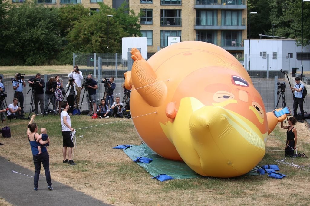 Activists inflate a giant balloon depicting US President Donald Trump as an orange baby in north London on July 10, 2018 ahead of a demonstration in London to coincide with the visit of the US president. Photo by Isabel Infantes/AFP/Getty Images.