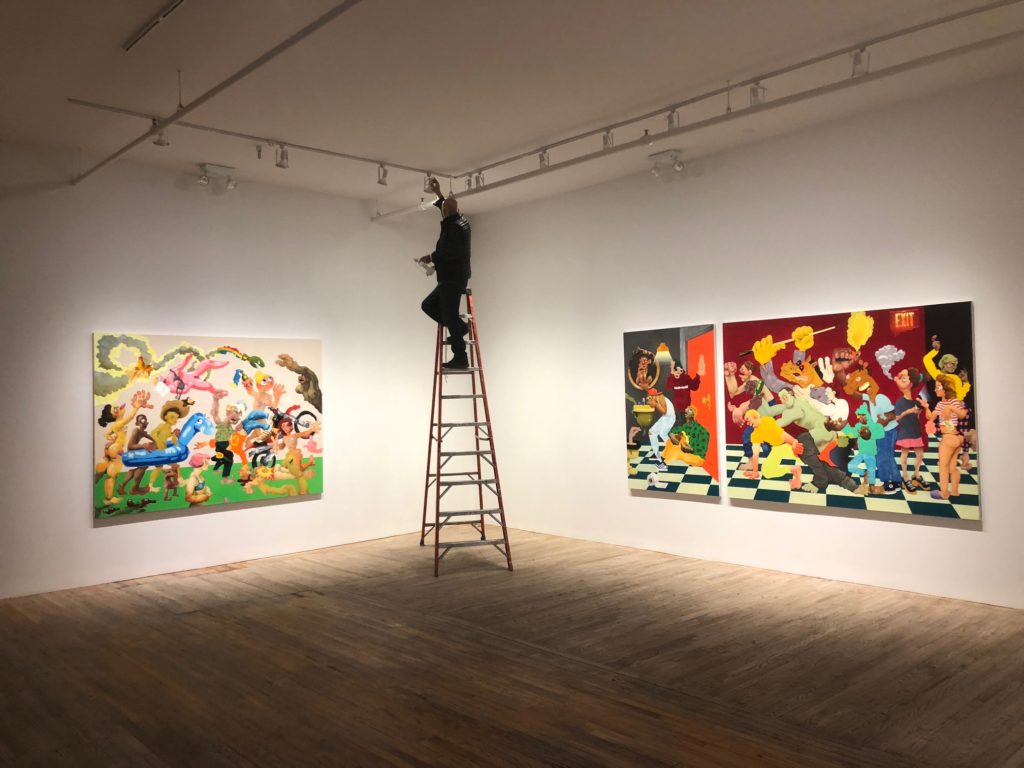 Postmasters co-founder Tamas Banovich lighting Canyon Castator's January 2018 solo exhibition, "Pissing Match," at the gallery. Image courtesy of Postmasters.