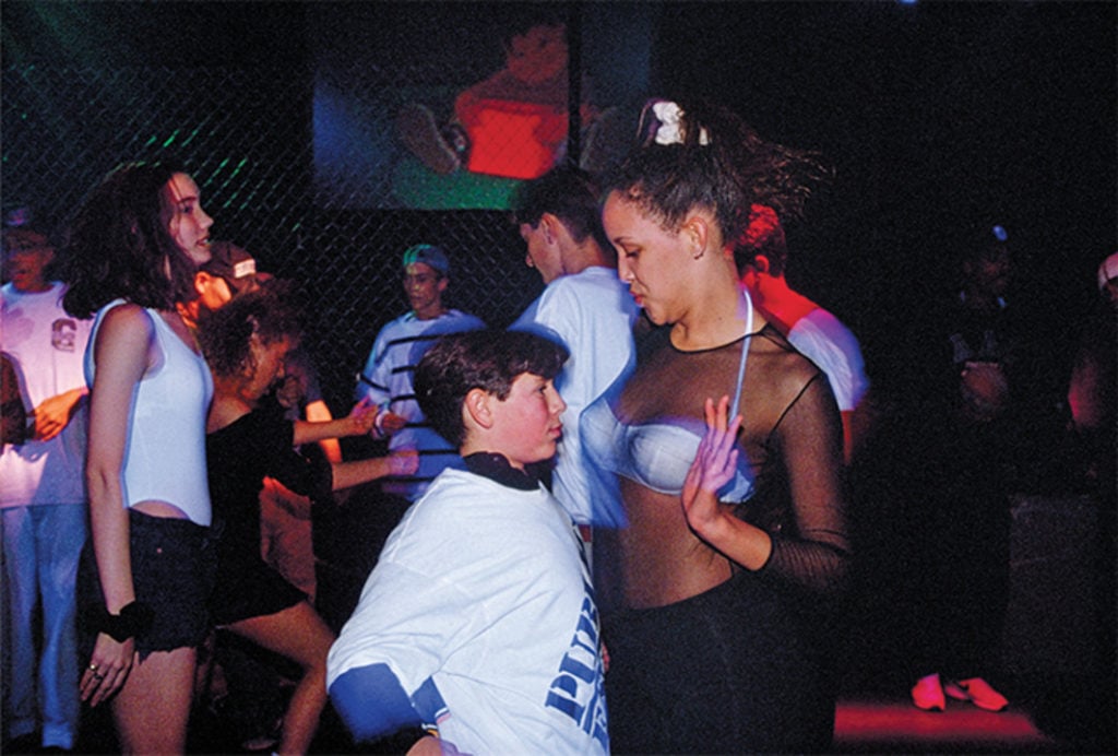 Adam, 13, and a go-go dancer hired to entertain at a bar mitzvah party at the Whisky a Go Go nightclub in West Hollywood, 1992. Featured in Lauren Greenfield's <em>Generation Wealth</em>. Photo courtesy of Amazon Studios ©Lauren Greenfield, all rights reserved.