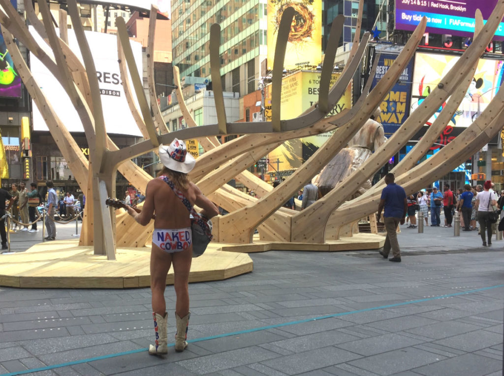 The famed Naked Cowboy plays in front of Mel Chin's Wake in Times Square. Image courtesy Ben Davis.