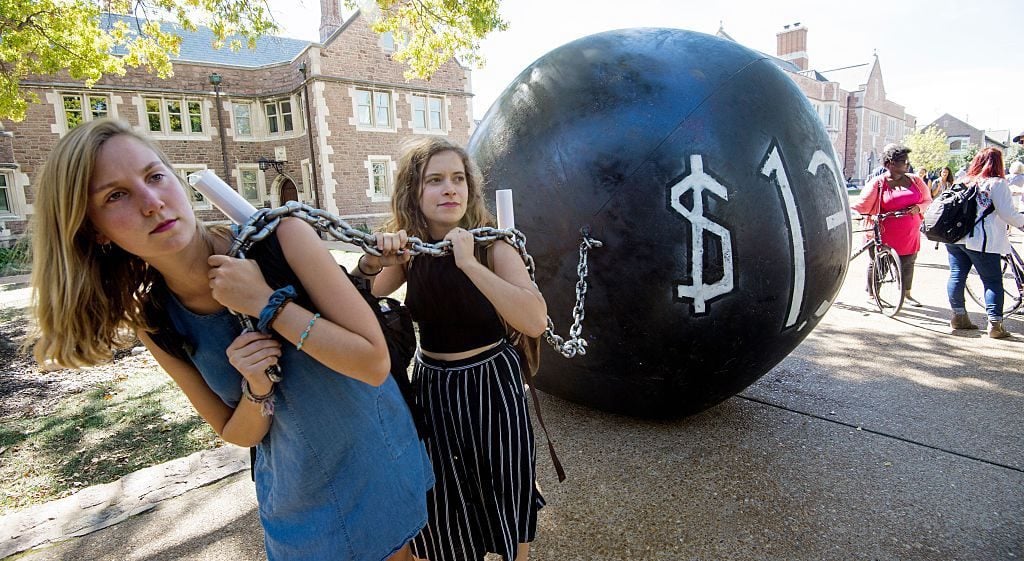 Students pull a mock "ball and chain" representing the $1.4 trilling outstanding student debt outside the second presidential debate 2016. Image courtesy Paul J. Richards/AFP/Getty Images.