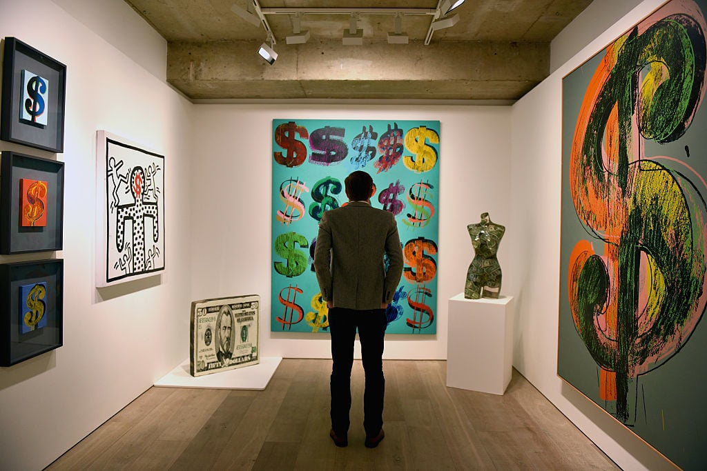 A visitor studies Dollar Signs (1981) by Andy Warhol for “The Art of Making Money” at Sotheby's on June 8, 2015 in London. Photo courtesy Mary Turner/Getty Images.