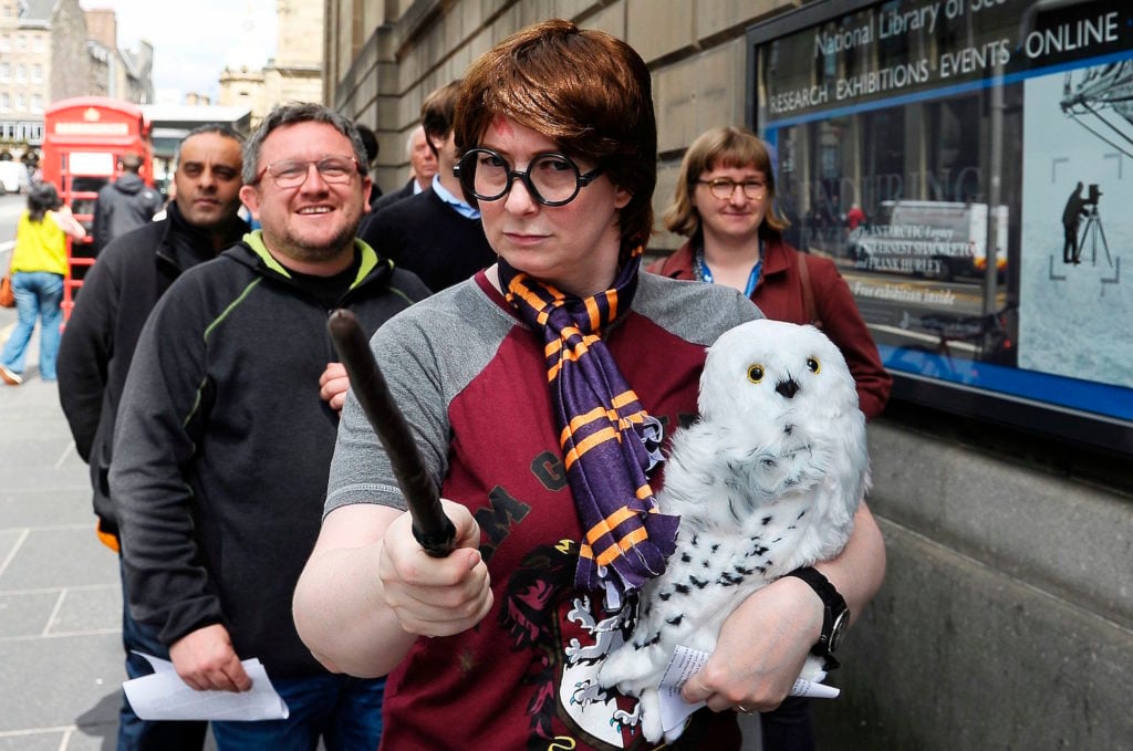 Fans of the Harry Potter books in line outside the National Library of Scotland in Edinburgh, Scotland in 2017, waiting to see a rare copy of <em>Harry Potter and the Philosopher's Stone</em> filled with personal notes and drawings by its author, J.K. Rowling. Photo by Neil Hanna/AFP/Getty Images.